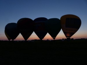 Fünf Heißluftballons vor dem Sonnenuntergang auf einem Feld im Wangerland.